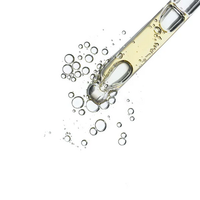 Close up of serum dispensing from a dropper on a white background